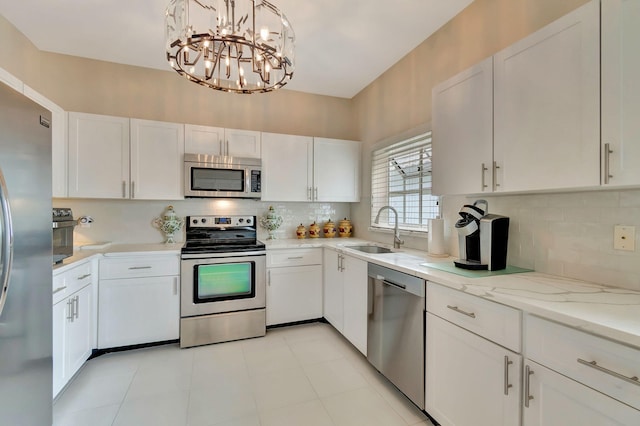 kitchen featuring white cabinets, an inviting chandelier, stainless steel appliances, sink, and pendant lighting