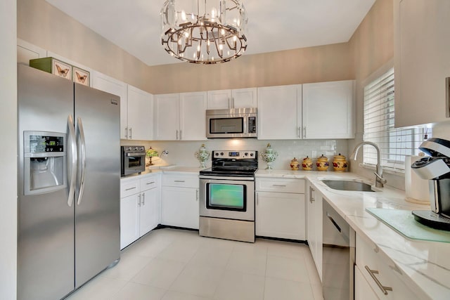 kitchen featuring a notable chandelier, stainless steel appliances, sink, hanging light fixtures, and white cabinets