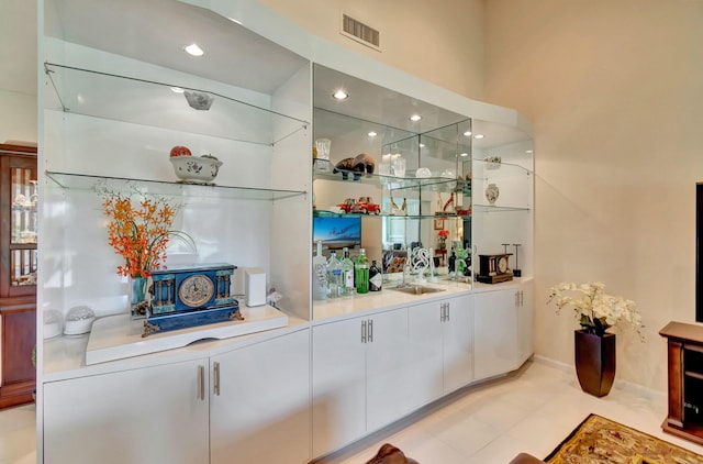 bar featuring light tile patterned floors, white cabinetry, and sink