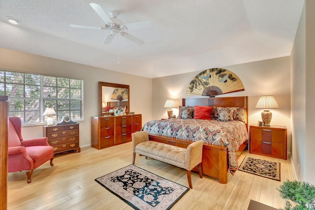 bedroom with a textured ceiling, ceiling fan, and light hardwood / wood-style floors