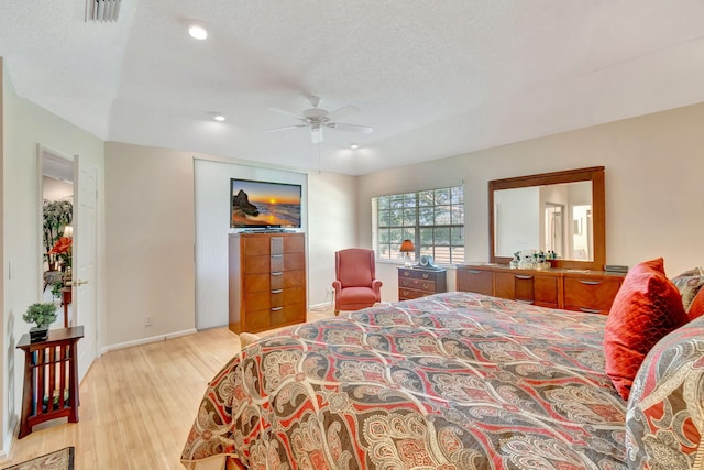 bedroom with ceiling fan, a textured ceiling, and light hardwood / wood-style flooring