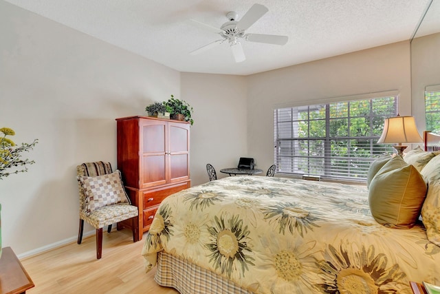 bedroom with a textured ceiling, light hardwood / wood-style flooring, ceiling fan, and multiple windows