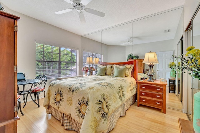 bedroom featuring ceiling fan, light hardwood / wood-style floors, and a textured ceiling