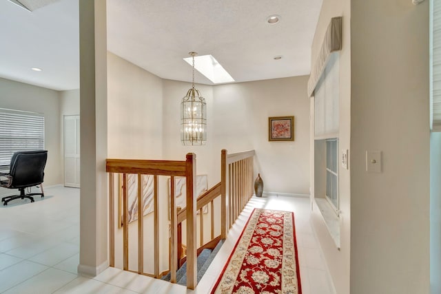 hallway featuring a textured ceiling, a skylight, a chandelier, and light tile patterned flooring