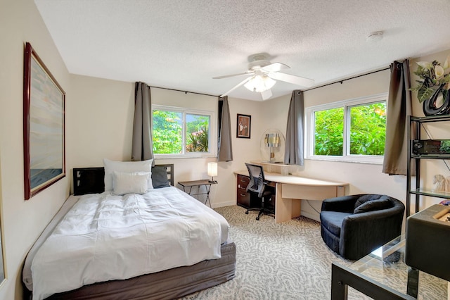 bedroom with multiple windows, ceiling fan, light carpet, and a textured ceiling