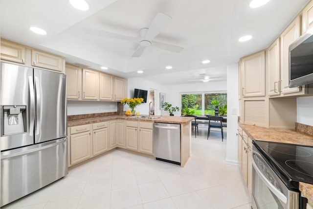 kitchen with a raised ceiling, sink, ceiling fan, appliances with stainless steel finishes, and kitchen peninsula