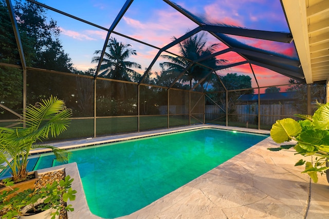 pool at dusk with a patio and a lanai