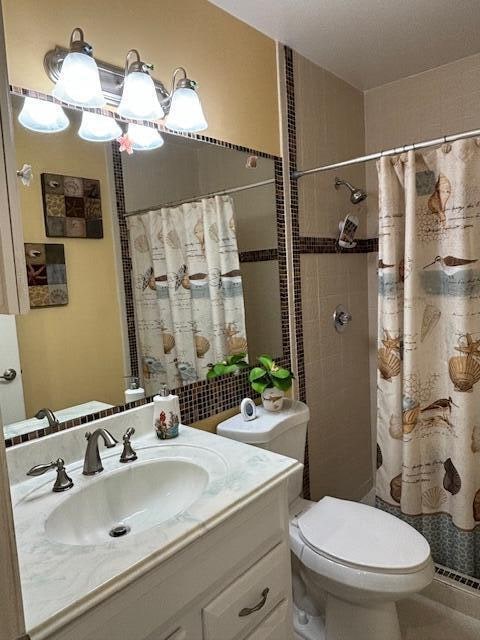 bathroom featuring walk in shower, toilet, and vanity