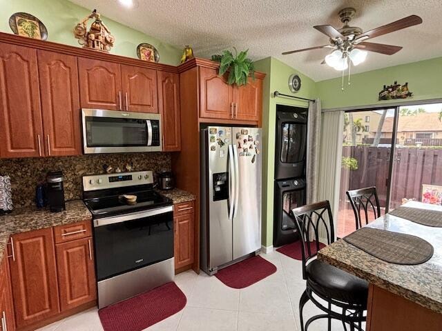 kitchen featuring appliances with stainless steel finishes, stone counters, and ceiling fan