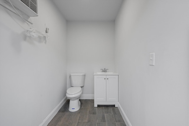 bathroom featuring a wall unit AC, vanity, hardwood / wood-style flooring, and toilet