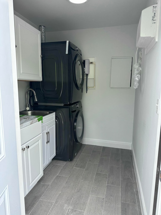 laundry area with stacked washer / drying machine, cabinets, sink, and light hardwood / wood-style floors