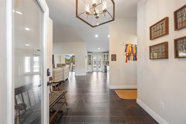 corridor with dark hardwood / wood-style flooring and an inviting chandelier