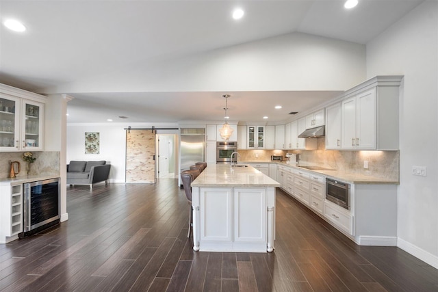 kitchen featuring built in appliances, decorative light fixtures, beverage cooler, white cabinets, and a barn door