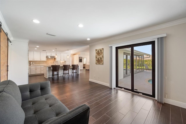 living room featuring ornamental molding, a barn door, and dark hardwood / wood-style floors