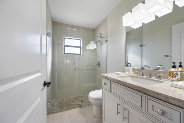 bathroom featuring a shower with shower door, vanity, toilet, and tile patterned floors