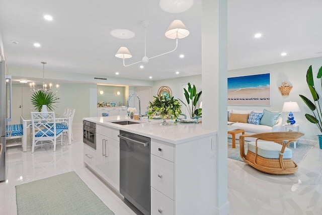 kitchen with stainless steel appliances, sink, pendant lighting, an inviting chandelier, and white cabinets