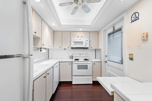 kitchen with white appliances, dark hardwood / wood-style floors, a raised ceiling, ceiling fan, and ornamental molding