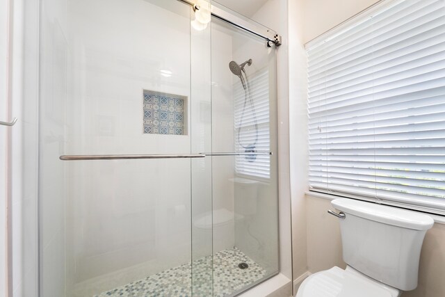 bathroom featuring toilet and a shower with door