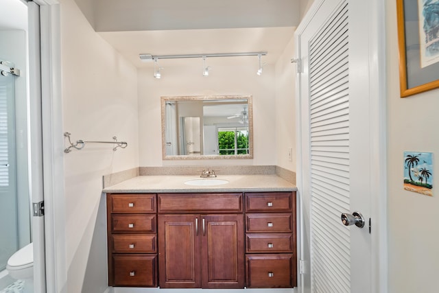bathroom featuring track lighting, toilet, and vanity
