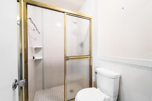 full bathroom with toilet, a shower stall, and tile walls