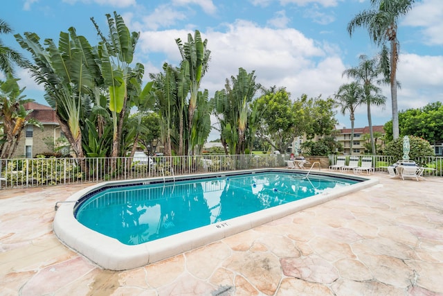 community pool with fence and a patio area