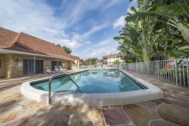 community pool with fence and a patio area
