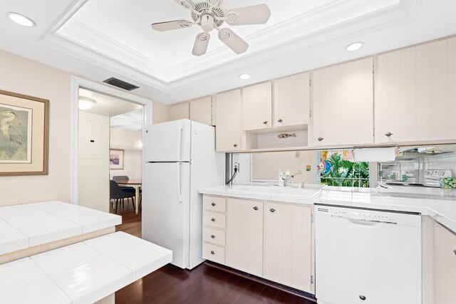 kitchen with white appliances, a sink, tile counters, a tray ceiling, and dark wood-style floors