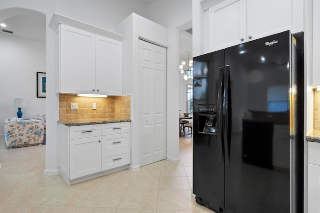 kitchen with light tile patterned floors, white cabinetry, black refrigerator with ice dispenser, and tasteful backsplash