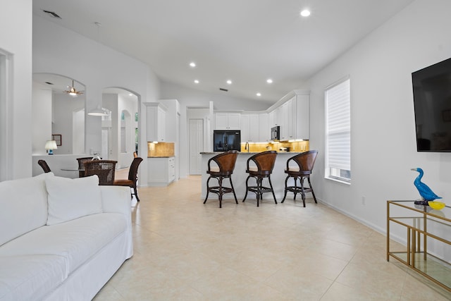 tiled living room featuring ceiling fan and lofted ceiling