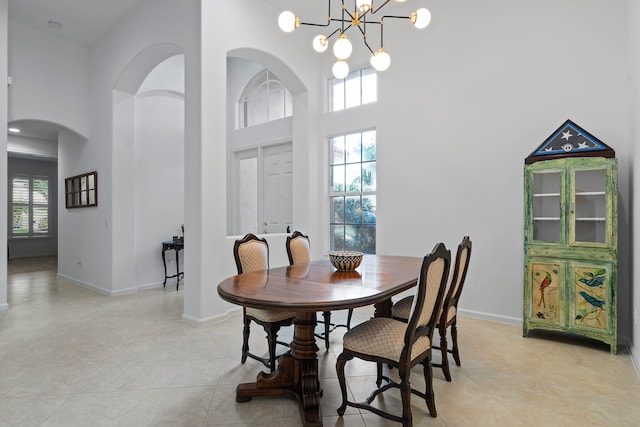 dining room featuring a notable chandelier, a healthy amount of sunlight, and a high ceiling