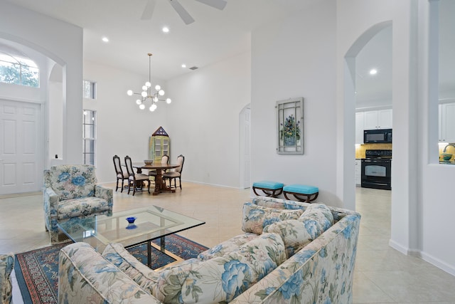 tiled living room featuring ceiling fan with notable chandelier and a high ceiling