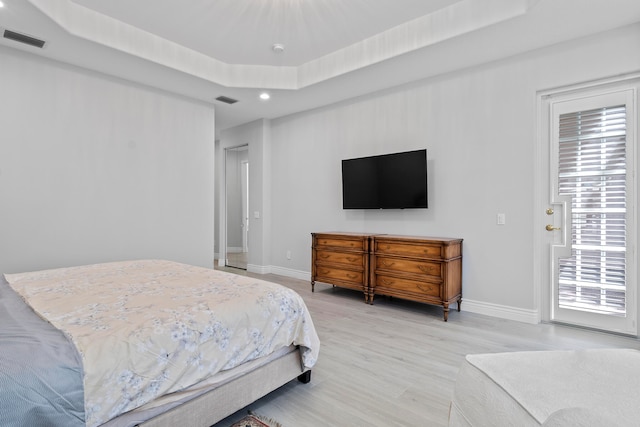 bedroom with a tray ceiling and light hardwood / wood-style flooring