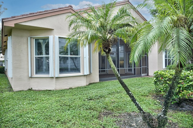 rear view of house with a lawn and a sunroom