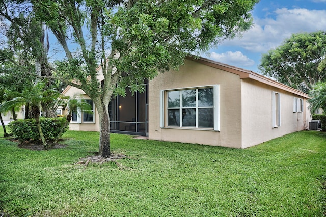 view of property exterior with a lawn, a sunroom, and cooling unit