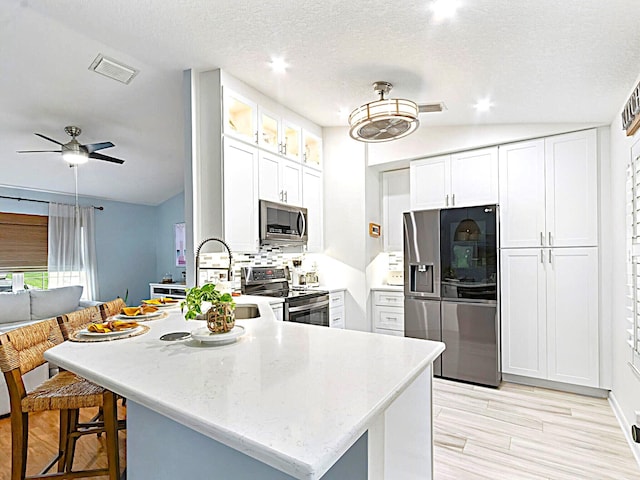 kitchen with white cabinets, ceiling fan, stainless steel appliances, and a textured ceiling