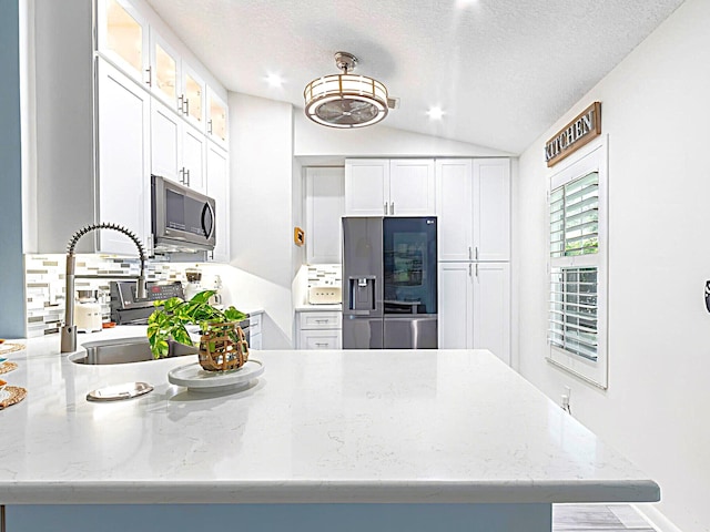 222 SW Starfish Ave, Port Saint Lucie, FL 34984 - kitchen with appliances with stainless steel finishes, white cabinets, a sink, glass insert cabinets, and vaulted ceiling