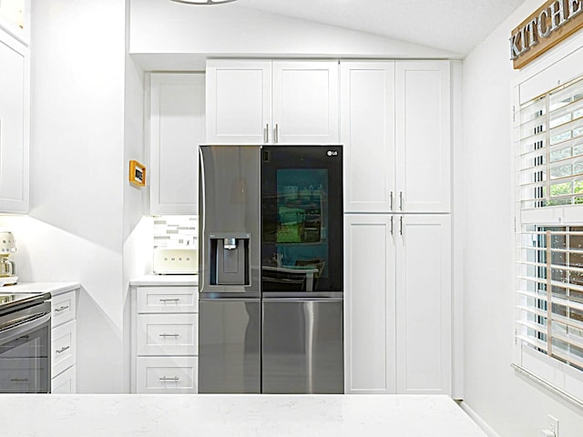 kitchen featuring appliances with stainless steel finishes, lofted ceiling, and white cabinets