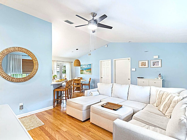 living room with ceiling fan, light hardwood / wood-style floors, and vaulted ceiling