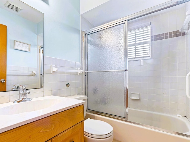 full bathroom featuring toilet, combined bath / shower with glass door, vanity, backsplash, and tile walls