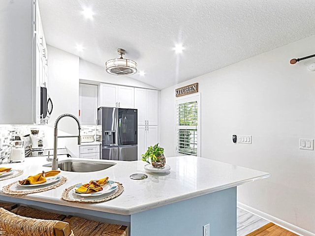 kitchen featuring sink, light wood-type flooring, stainless steel fridge with ice dispenser, and a textured ceiling