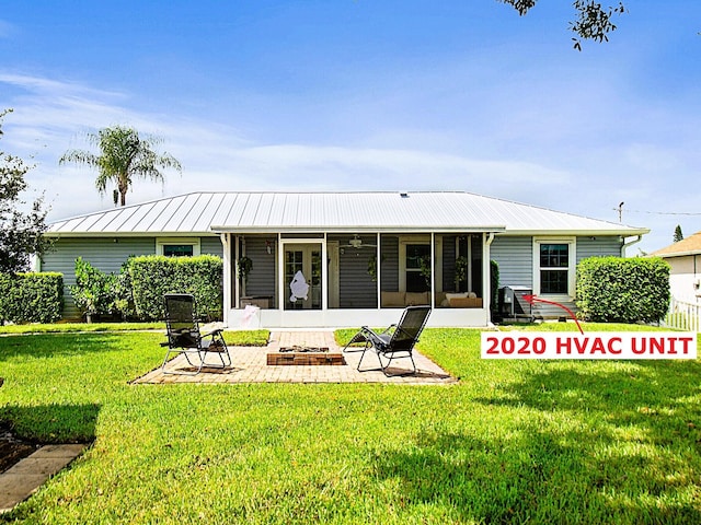 back of property with a patio area, an outdoor fire pit, a yard, and a sunroom