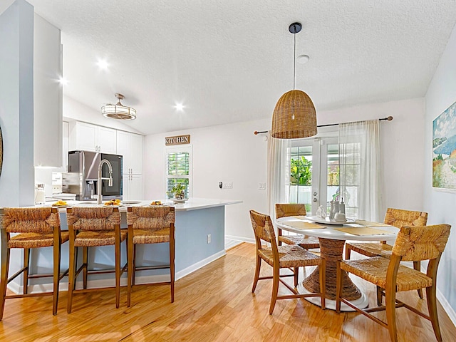 dining area with plenty of natural light, light hardwood / wood-style floors, and a textured ceiling