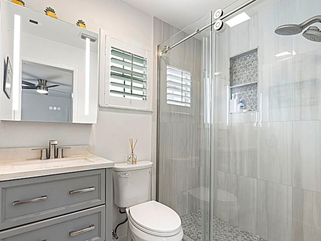 bathroom featuring vanity, toilet, walk in shower, and ceiling fan