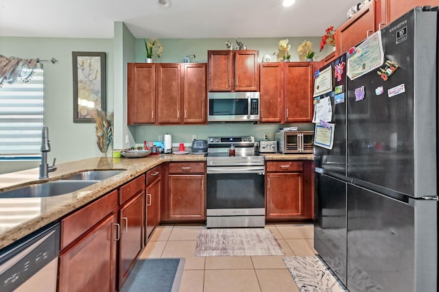 kitchen with light tile patterned flooring, appliances with stainless steel finishes, light stone counters, and sink