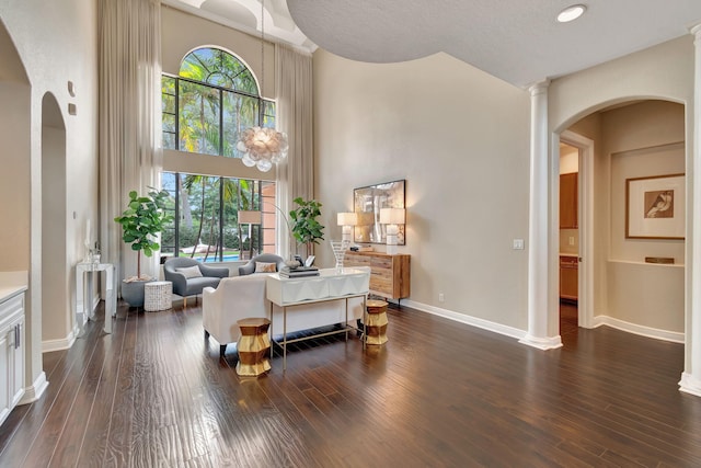 living room featuring dark wood-type flooring, a textured ceiling, and a towering ceiling