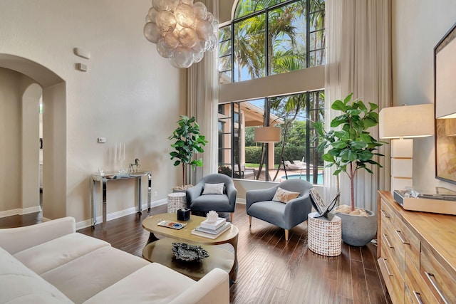 living room featuring a towering ceiling, dark hardwood / wood-style floors, and an inviting chandelier