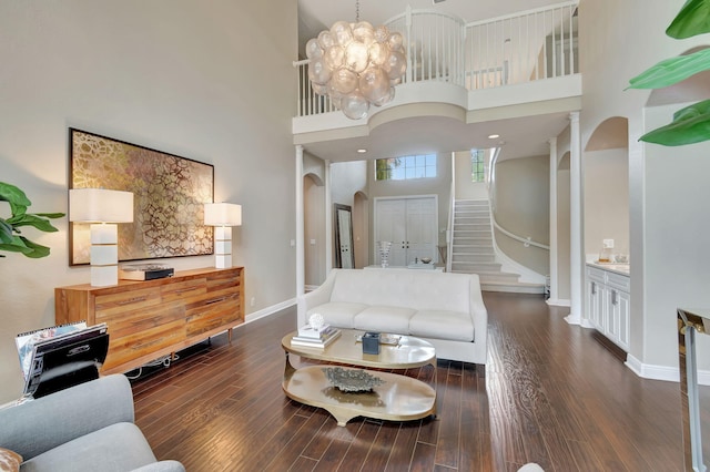 living room featuring a towering ceiling, dark hardwood / wood-style flooring, and a chandelier