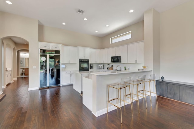 16106 Rosecroft Ter, Delray Beach, FL 33446 - kitchen with visible vents, arched walkways, a high ceiling, light countertops, and black appliances