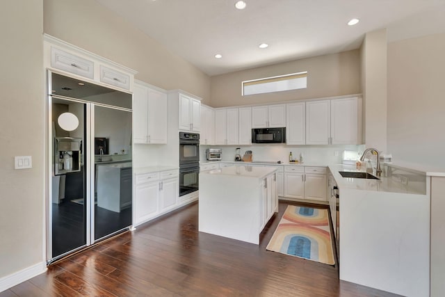 kitchen featuring white cabinets, a center island, sink, black appliances, and dark hardwood / wood-style floors