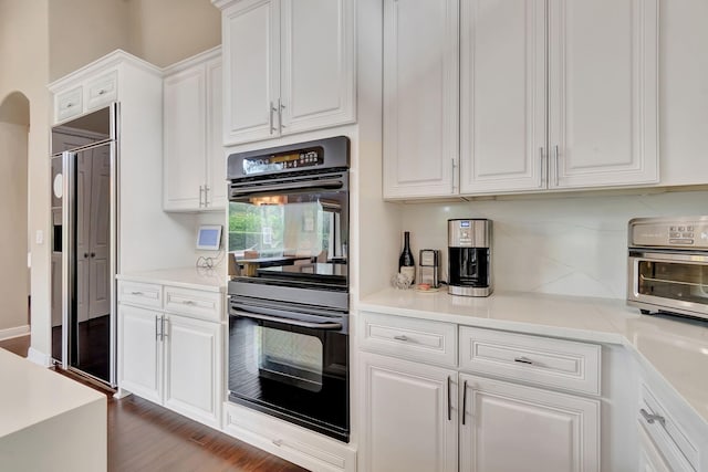 kitchen featuring dark hardwood / wood-style flooring, built in refrigerator, white cabinetry, and black double oven